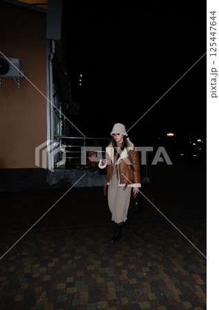 Nighttime urban stroll highlighting a fashionable figure in a chic outfit walking calmly through a lively city street filled with soft lights and shadows Nighttime urban stroll highlighting a fashionable figure in a chic outfit walking calmly through a lively city street filled with soft lights and shadows 125447644