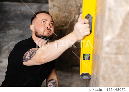 Construction worker using spirit level installing marble tile on wall Construction worker using spirit level installing marble tile on wall 125448072