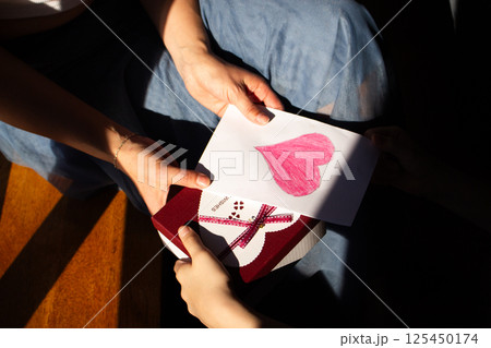 Happy mother's day. Child daughter congratulates moms and gives her gift box and handmade greeting card. 125450174