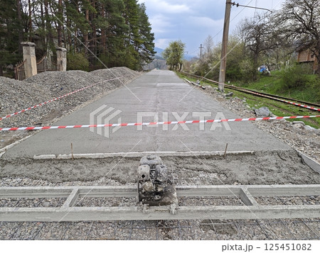 Workers constructing new concrete road near railroad tracks 125451082