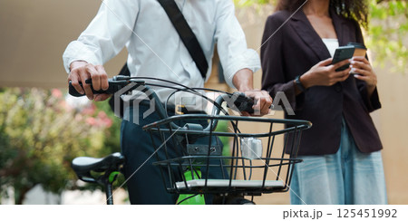 Sustainable Transport and Communication. A man on a bicycle engages with technology in an urban environment while a woman supports him. Sustainable Transport and Communication. A man on a bicycle engages with technology in an urban environment while a woman supports him. 125451992