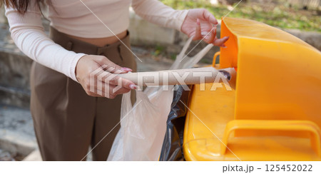 Waste Reduction and Recycling. A person inserting cardboard into a recycling bin, promoting eco-friendly practices. Waste Reduction and Recycling. A person inserting cardboard into a recycling bin, promoting eco-friendly practices. 125452022