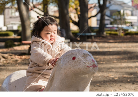 【冬の公園　遊具で遊ぶ1歳児】 125452076