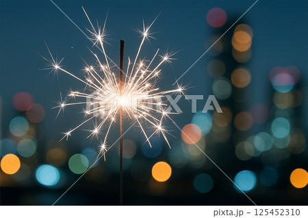 都市の夜景を背景に銀色の手持ち花火が輝く瞬間 125452310
