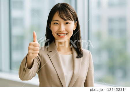 オフィスで笑顔とサムズアップを見せる日本人若手女性社員 125452314