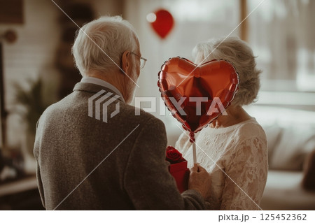 A man and woman are holding a red heart balloon 125452362