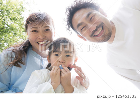 カメラをのぞき込む3人家族 クローズアップの笑顔 カメラをのぞき込む3人家族 クローズアップの笑顔 125453535