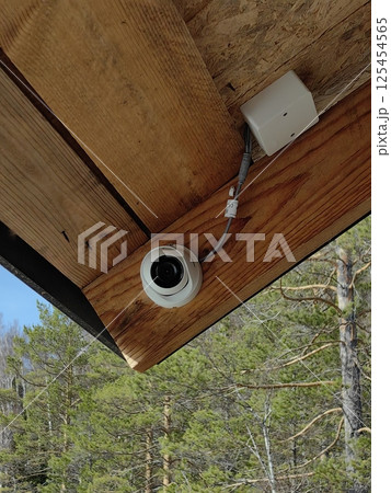 camera installed on wooden cabin eave in woods for security monitoring and wildlife observation. camera installed on wooden cabin eave in woods for security monitoring and wildlife observation. 125454565