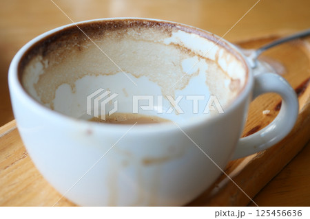 Coffee cup with remnants after enjoying a warm beverage in a cafe Coffee cup with remnants after enjoying a warm beverage in a cafe 125456636
