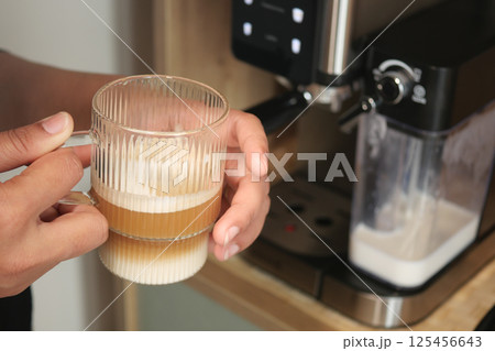 Coffee preparation with milk frothing at home in the morning hours 125456643