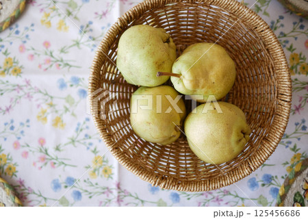 Fresh pears in a woven basket on a floral tablecloth 125456686