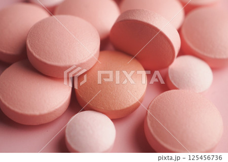 Pink round tablets displayed on a soft surface in close-up view Pink round tablets displayed on a soft surface in close-up view 125456736