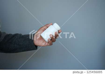 Person holding a small white container in a casual setting 125456895