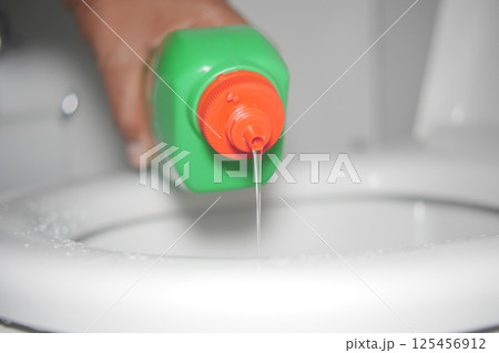 Cleaning solution being poured into a toilet for sanitation 125456912