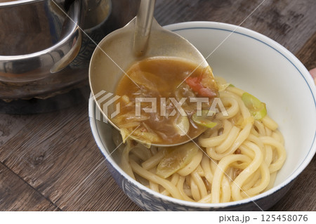 残り物のカレーで作ったカレーうどんを丼に盛り付ける 125458076