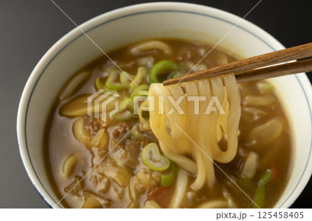 残り物のカレーで作ったカレーうどんを箸で持ち上げる 125458405