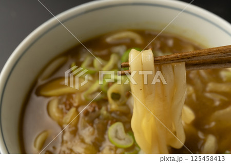 残り物のカレーで作ったカレーうどんを箸で持ち上げる 125458413