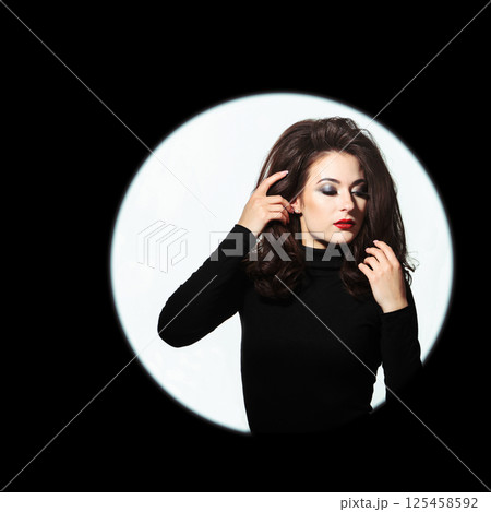 Beautiful woman standing in illuminated circle in black background 125458592