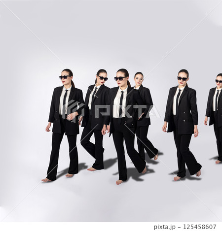 Group of same women in black suits walking on white background 125458607