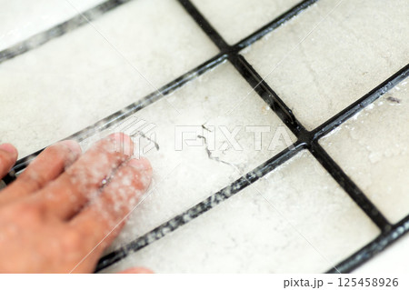 空気清浄機の汚れたフィルターを水洗いする手元 空気清浄機の汚れたフィルターを水洗いする手元 125458926