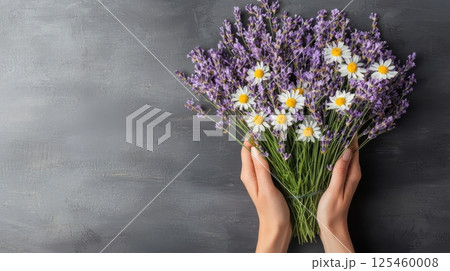 A person is holding a bouquet of flowers, including lavender and daisies 125460008