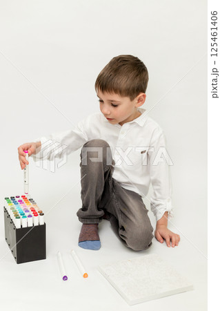 The boy takes the marker out of the package. Boy on a white background drawing The boy takes the marker out of the package. Boy on a white background drawing 125461406