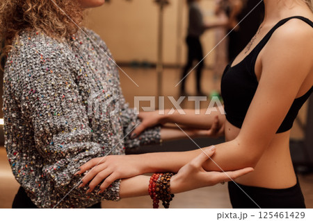 Two women play sports.The trainer supports the client by the hands.Physiotherapy 125461429