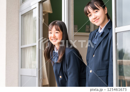 学校の教室の窓際で会話する中学生の女子生徒 125461673