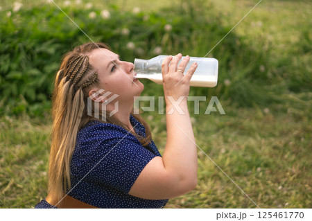 A woman blissfully enjoying a refreshing drink while immersed in the beauty of nature outside 125461770