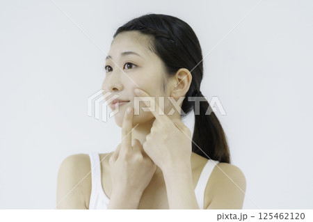 白背景の口元のツボを押す若い女性の顔のアップ 白背景の口元のツボを押す若い女性の顔のアップ 125462120