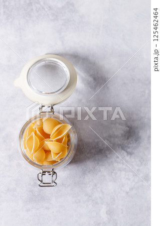 Raw uncooked dried Conchiglie shell pasta. Italian seashells pasta in lock lid jar on white background. 125462464