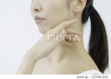白背景の頬に手を当てる若い女性の顔のアップ 白背景の頬に手を当てる若い女性の顔のアップ 125463161