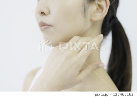 白背景の頬に手を当てる若い女性の顔のアップ 125463162