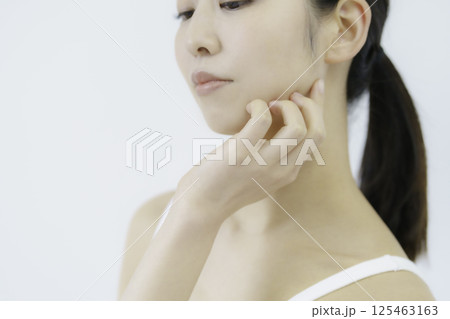白背景の頬に手を当てる若い女性の顔のアップ 白背景の頬に手を当てる若い女性の顔のアップ 125463163