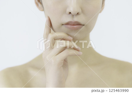 白背景の頬に手を当てる若い女性の顔のアップ 白背景の頬に手を当てる若い女性の顔のアップ 125463990