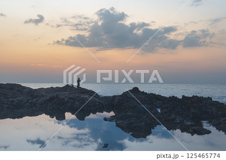 Seascape in Thailand kaolak. Rocky coastal ridge on the background of sunset, panorama. A small silhouette of a fisherman on the rocks. Seascape in Thailand kaolak. Rocky coastal ridge on the background of sunset, panorama. A small silhouette of a fisherman on the rocks. 125465774