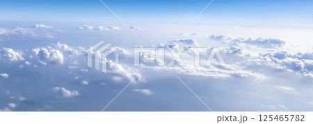 Heavenly purity panoramic background - beautiful white real clouds in the deep sky, view from an airplane. 125465782
