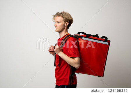Side profile of courier in red uniform with thermal bag Side profile of courier in red uniform with thermal bag 125466385
