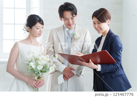 新郎新婦と話す結婚式場スタッフ 新郎新婦と話す結婚式場スタッフ 125467776