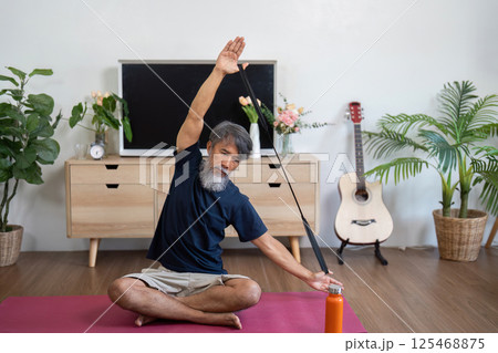 Wellness exercises for elderly man stretching at home Wellness exercises for elderly man stretching at home 125468875