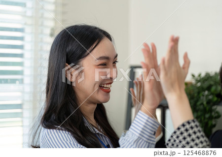 Joyful businesswoman celebrating with colleagues after a successful handshake, showcasing teamwork and positive relationships. Joyful businesswoman celebrating with colleagues after a successful handshake, showcasing teamwork and positive relationships. 125468876