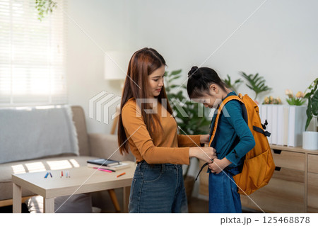 Back to School and Preparation Time. A mother helps her daughter adjust her backpack before she goes to school. Back to School and Preparation Time. A mother helps her daughter adjust her backpack before she goes to school. 125468878