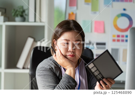 Diverse graphic designer thoughtfully reviewing color palette options in workspace. Diverse graphic designer thoughtfully reviewing color palette options in workspace. 125468890
