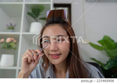 Beauty Tools and Eye Makeup. A woman preparing her look with an eyelash curler. 125468906
