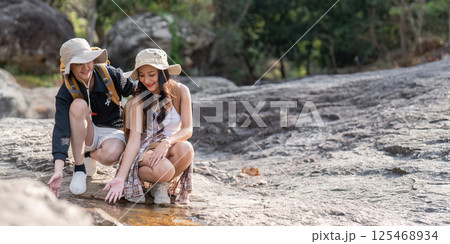 LGBT couple exploring a rocky stream during their hiking adventure in nature 125468934