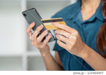 Finances and Smart Spending. A woman managing her funds by using her credit card while checking her smartphone. Finances and Smart Spending. A woman managing her funds by using her credit card while checking her smartphone. 125468947
