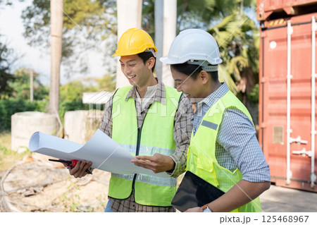 Logistics engineer collaboration on project plans construction site professional meeting outdoor environment focused viewpoint Logistics engineer collaboration on project plans construction site professional meeting outdoor environment focused viewpoint 125468967