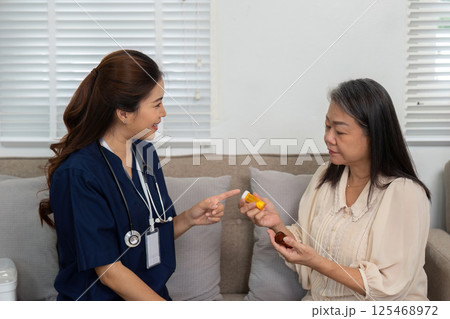 Nursing and Elderly Interaction. A caregiver assists an elderly woman with her medication in a nurturing home environment. 125468972