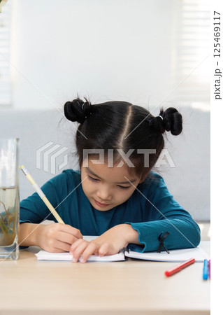 Back to School and Studying. A young girl focused on her homework with stationery around her. 125469117