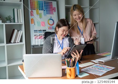 Dynamic graphic design team collaborating on projects with digital devices in a colorful studio 125469144